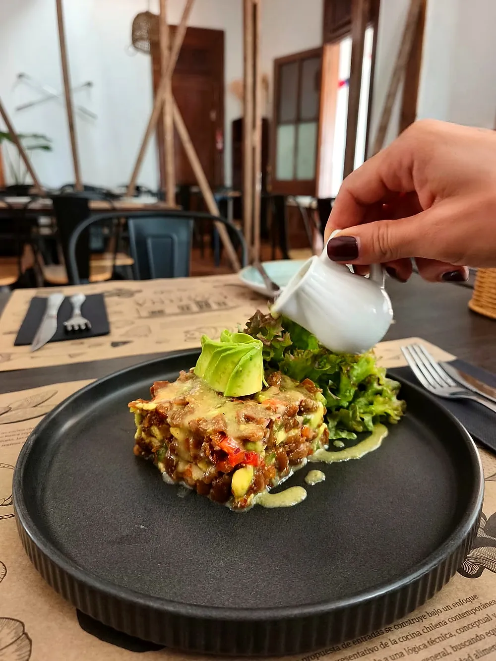 Plato servido en una vajilla negra mientras se vierte una salsa